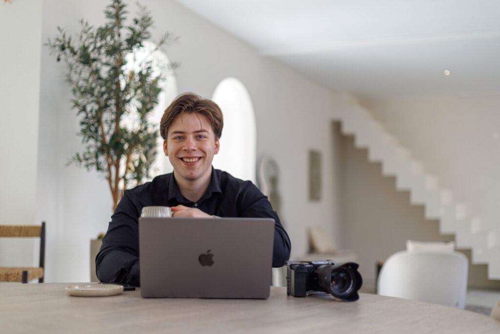 Liam van LVHVisuals aan tafel met laptop en camera